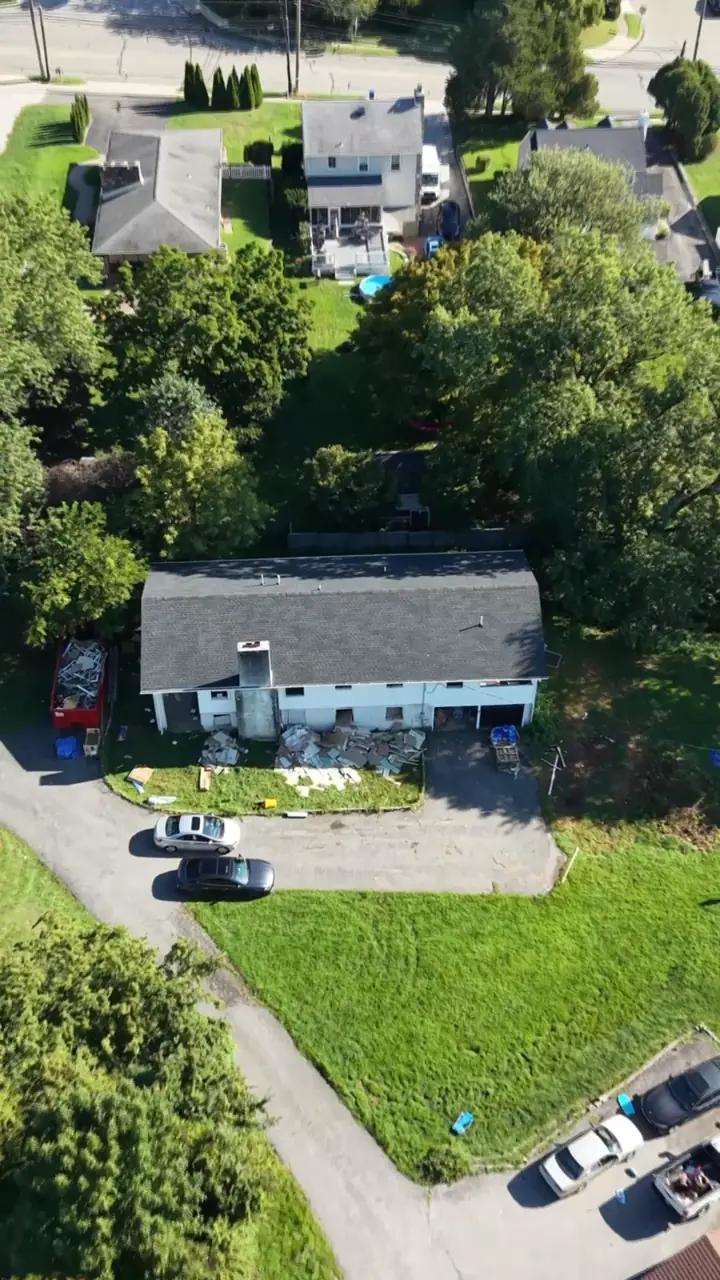 Drone view looking down on the house, its long driveway and the deep green lawn.