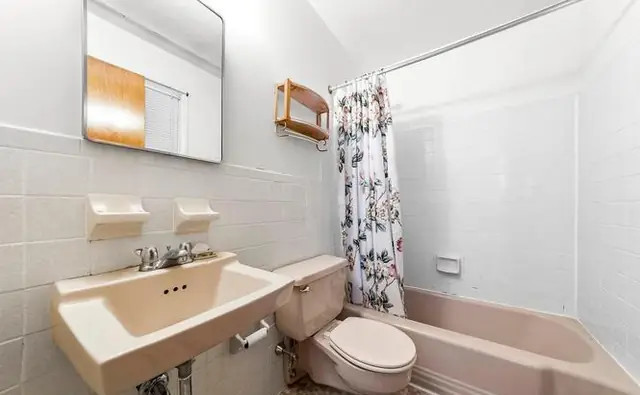 Before: a dated bathroom with a pink tub and pedestal-style sink.