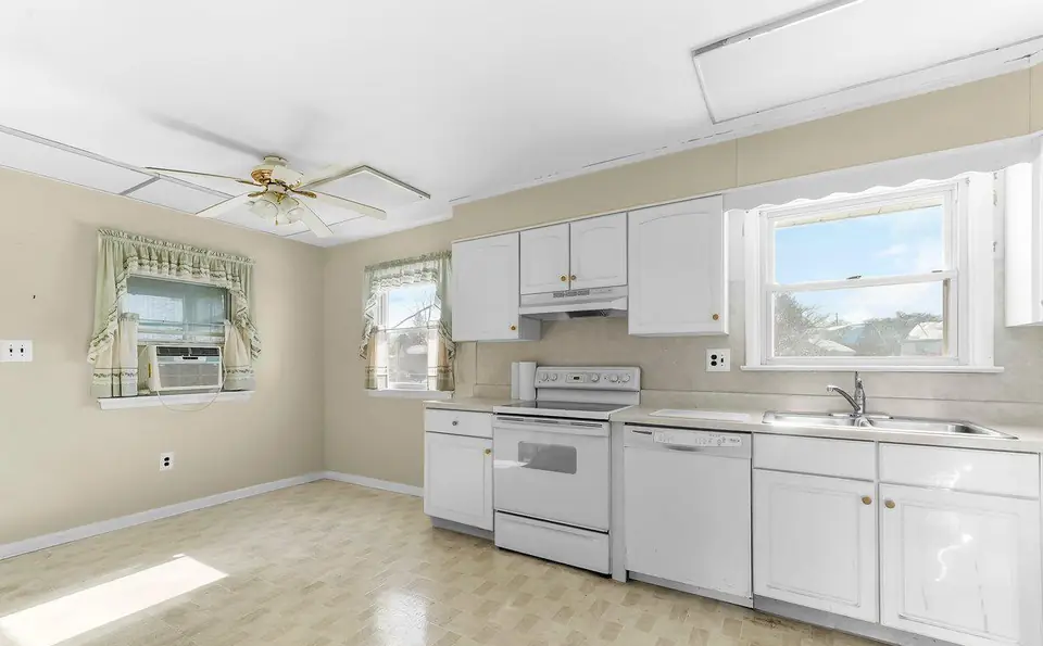 Before: a closed kitchen with white cabinets, vinyl floor and white appliances.
