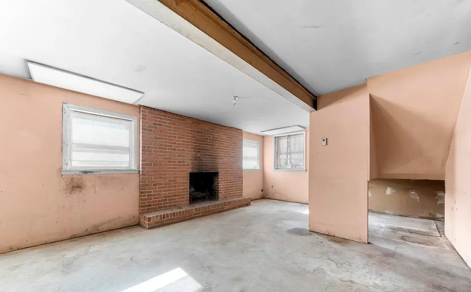 Before: the lower level with salmon walls, a brick fireplace and bare concrete.