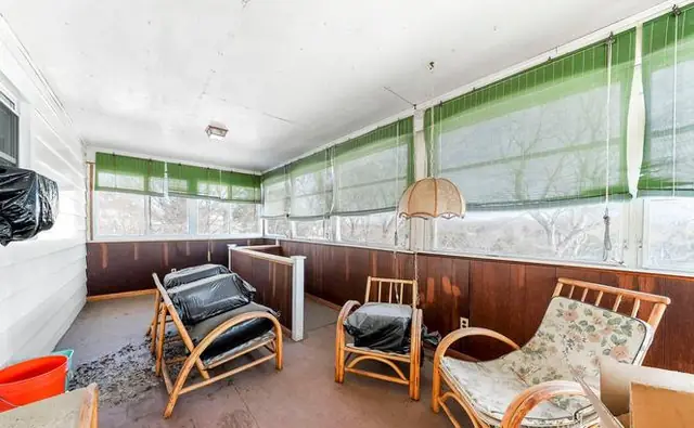 Before: the enclosed porch with green shades and worn flooring.