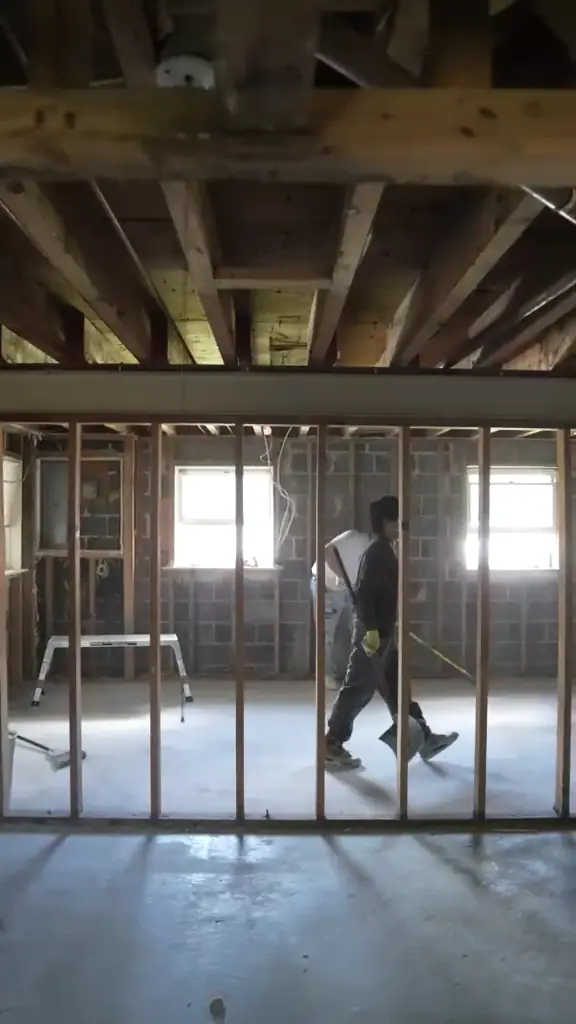 The lower level taken down to open framing with a worker carrying material.