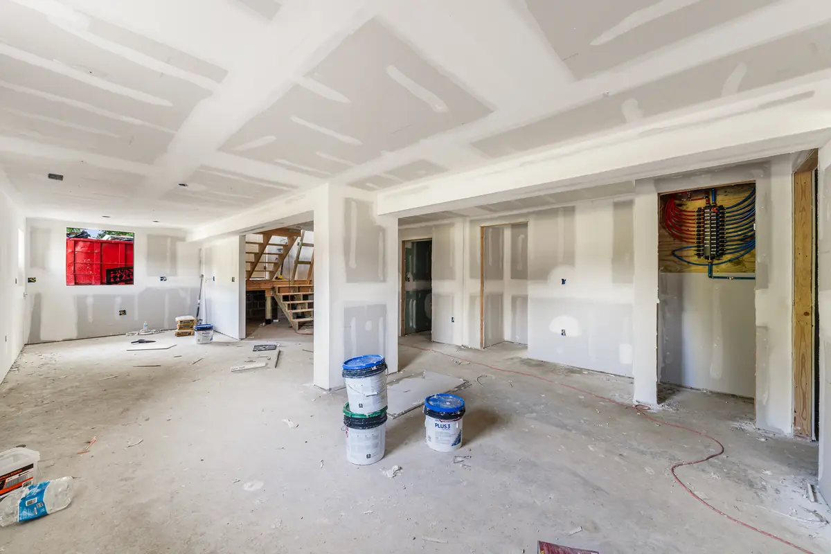 The walkout lower-level den in drywall, with the stair and the door to the yard.