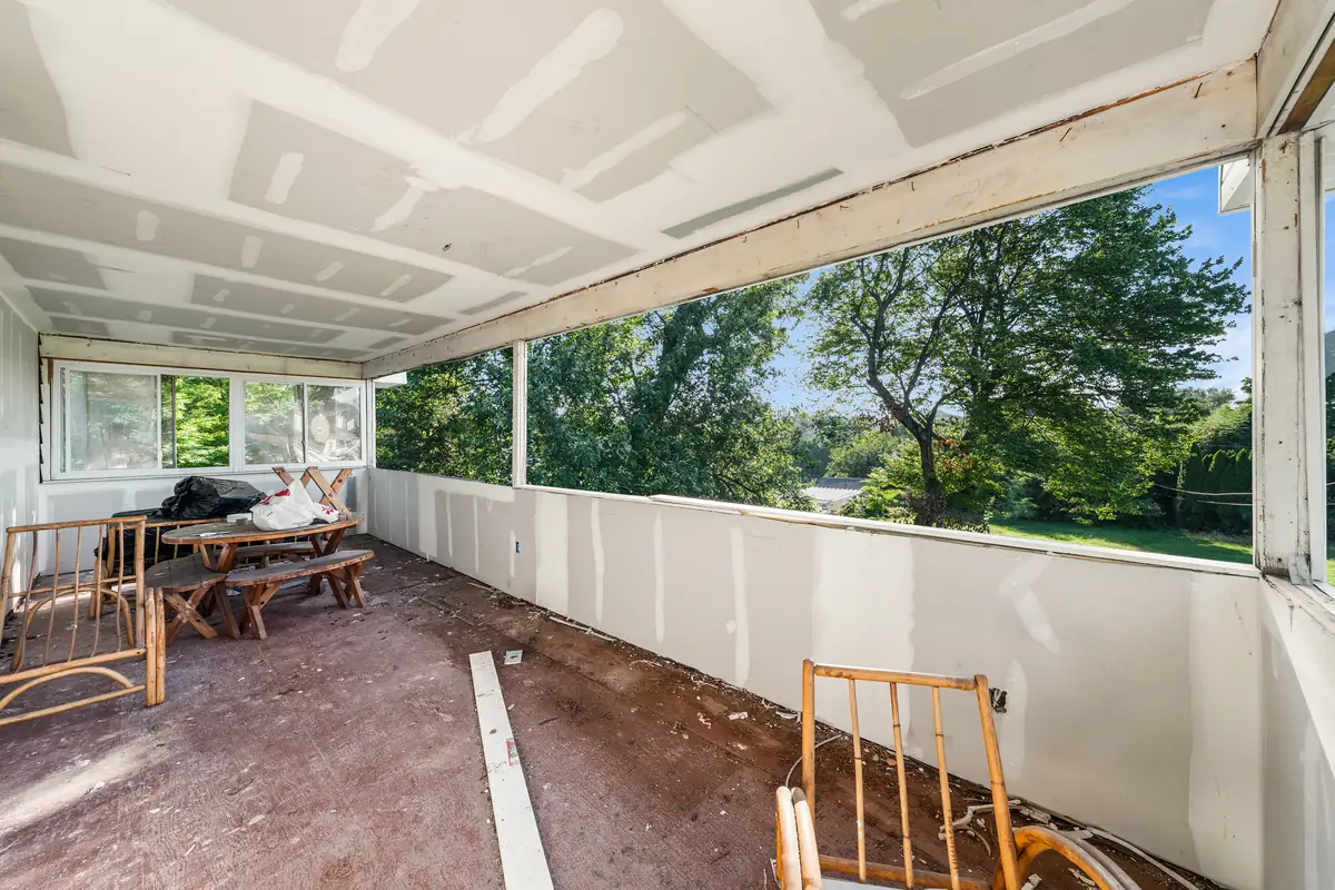 The sunroom with new drywall and a long run of windows looking over the yard and trees.