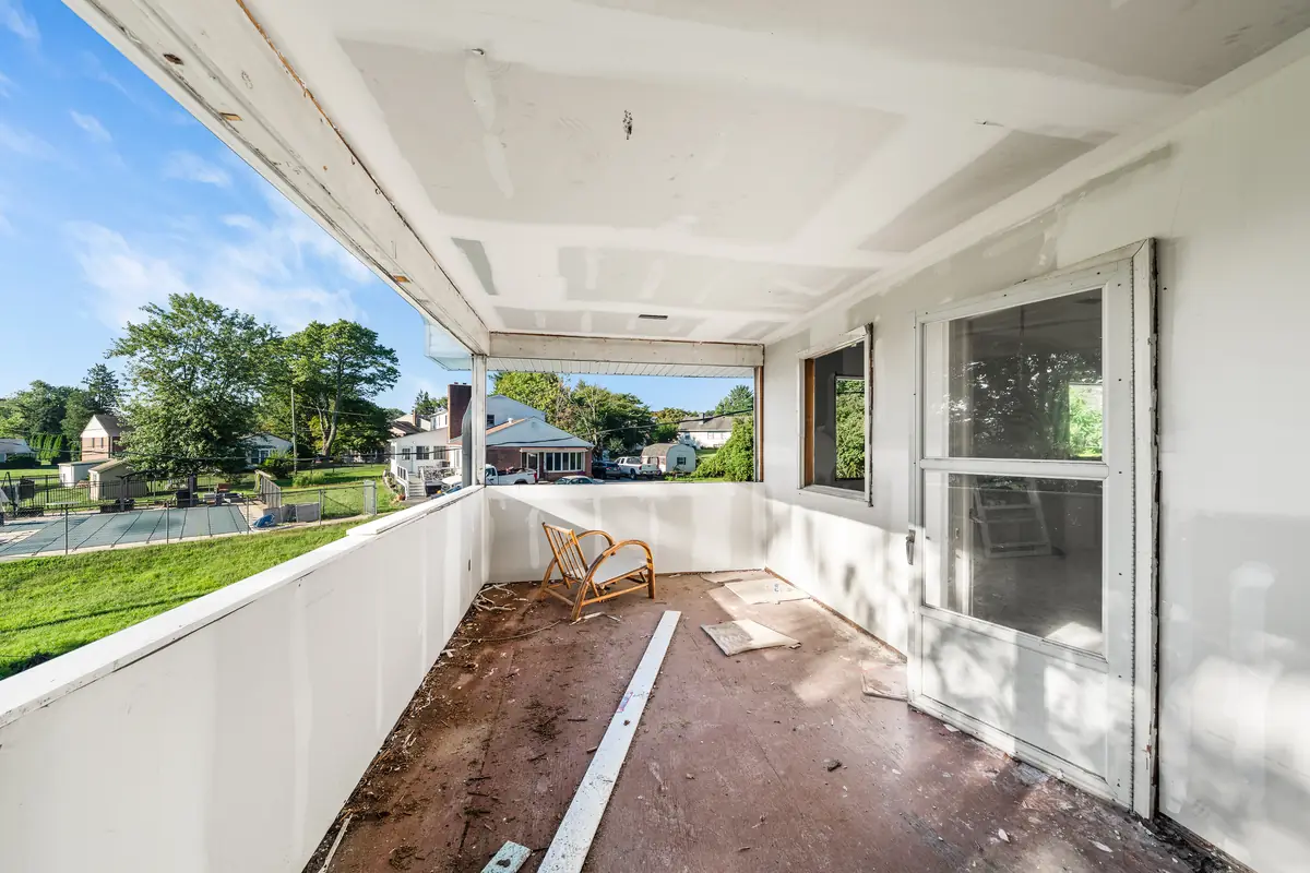 The sunroom with a long wall of windows facing the trees and lawn.